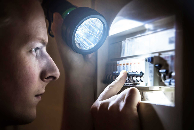 A electrician looking at an electrical panel