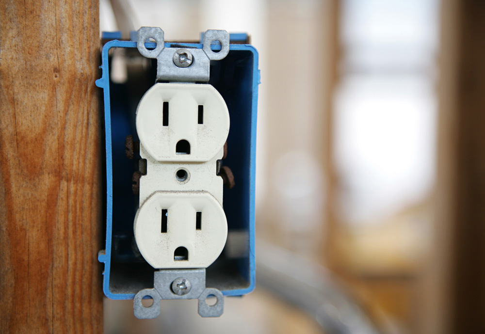 A blue and white electrical outlet attached to a wooden pole.